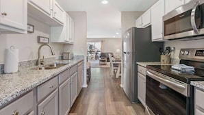A modern kitchen with granite countertops, stainless steel appliances, and light-colored cabinetry. - Hillside Duo | 2 Units in The Vineyards Resort (Branson)