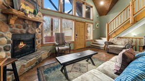 A cozy living room with a stone fireplace, a wooden bench, and a couch. - Royal Moose Lodge – A Grand Adventure for 20! (Branson)