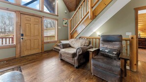 A spacious living area with a wooden staircase, two large doors, and a view of the outdoors. - Royal Moose Lodge – A Grand Adventure for 20! (Branson)