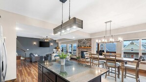 A modern kitchen with a central island, wooden flooring, and a dining area with a view.