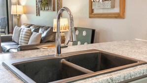 Eine Küche mit einem Doppelwaschbecken, einer Arbeitsplatte aus Granit und einem modernen Wasserhahn.
