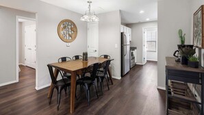 A modern kitchen with a dining area, featuring a wooden table, black chairs, and a chandelier. - Urban Farmhouse | Refreshing Pool! (Branson)