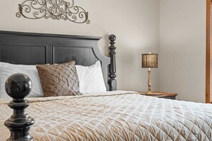 Uma cama bem arrumada com cobertura acolchoada, cabeceira de madeira escura e um objeto decorativo na parede acima.