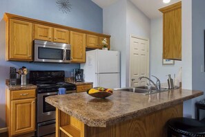 A kitchen with wooden cabinets, stainless steel appliances, granite countertops, and a fruit bowl.