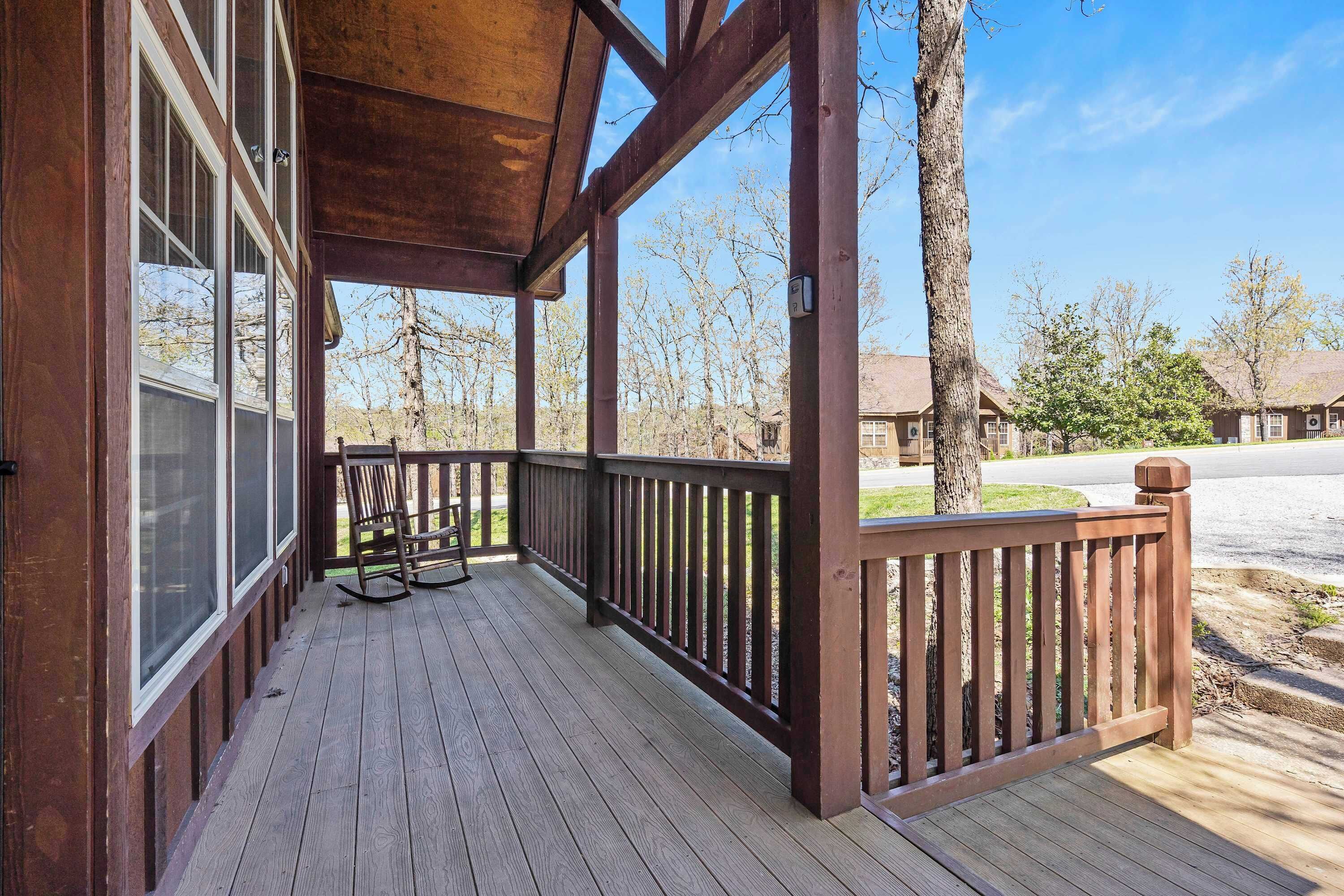 A wooden porch with a bench and a rocking chair, overlooking a residential street.