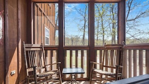 A wooden deck with two rocking chairs and a small table, overlooking a forested area. - Fox Hollow Family Lodge (Branson West)
