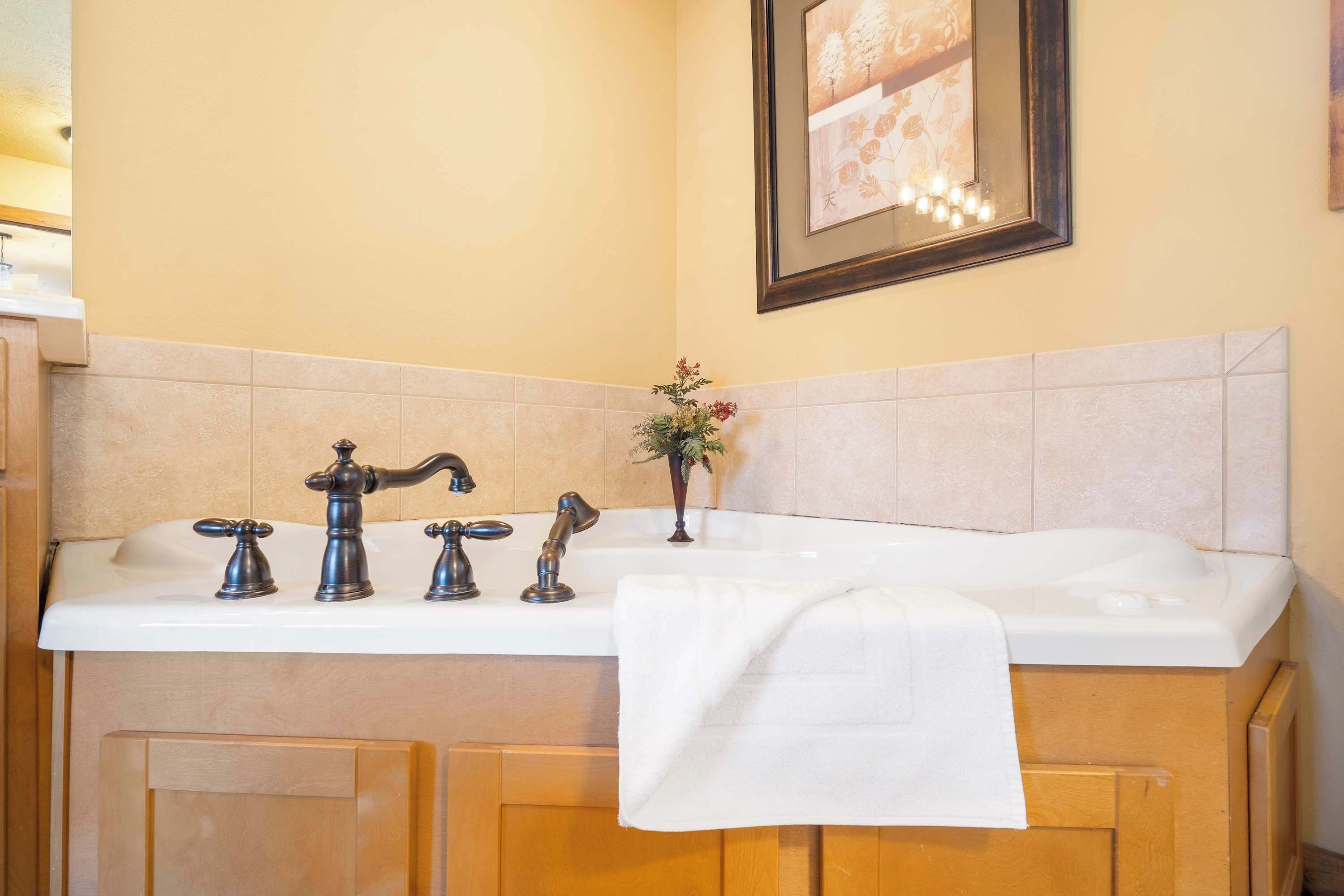 A bathroom with a white bathtub, two faucets, and a towel on the side.