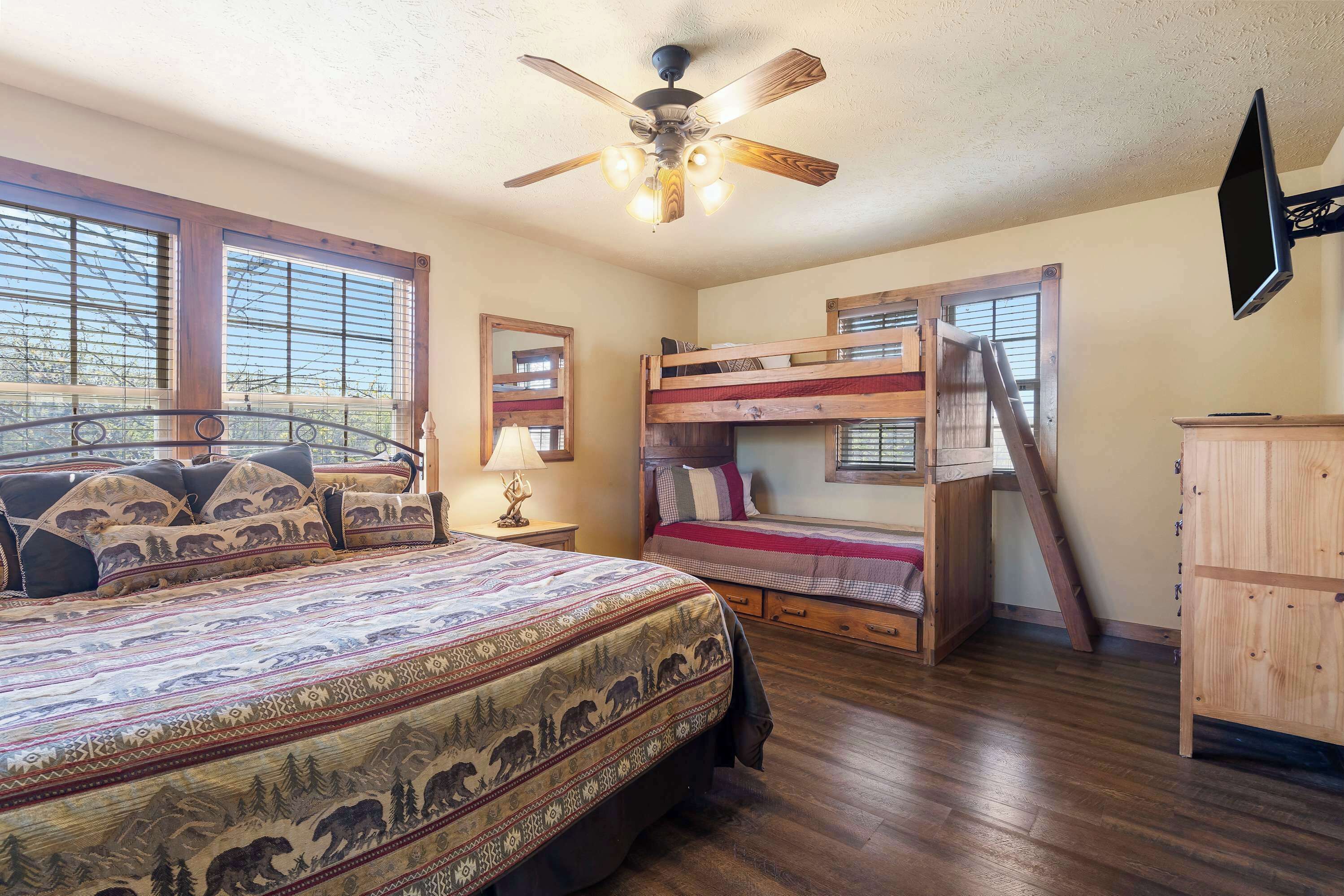 A bedroom with a large bed, a bunk bed, and a ceiling fan.