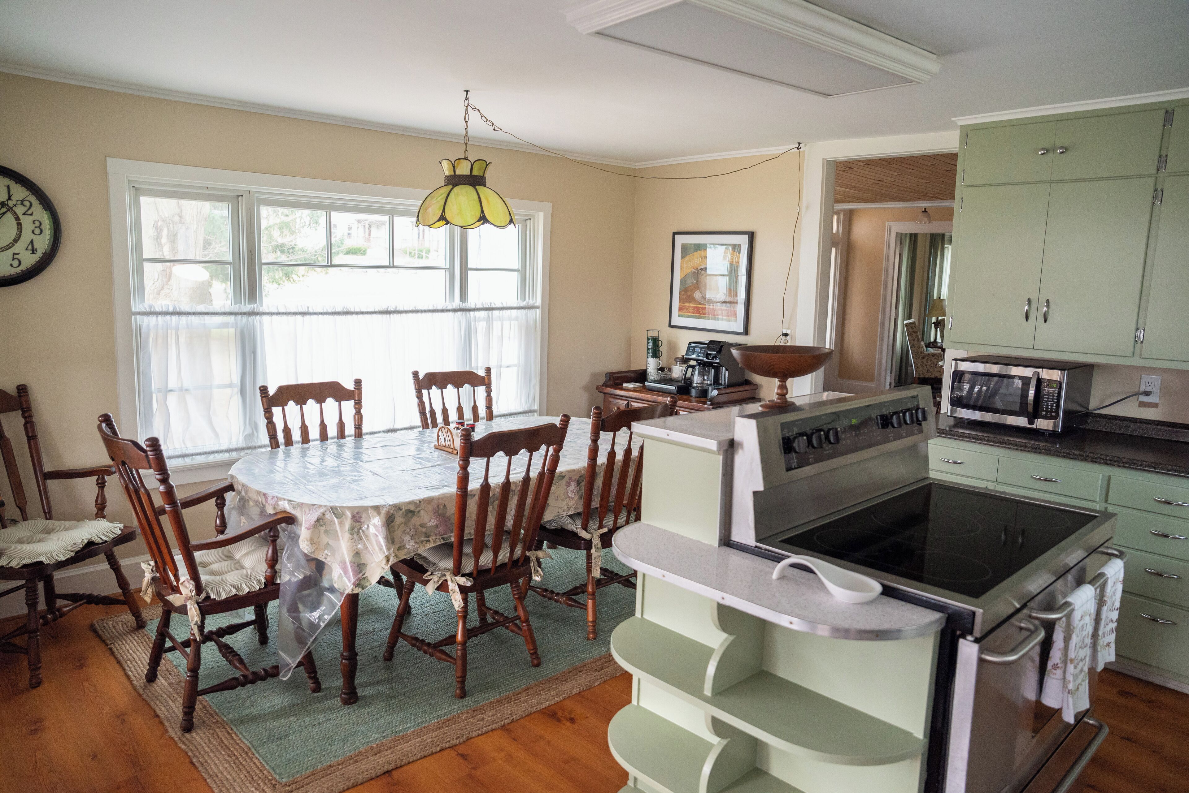 A kitchen with wooden chairs around a table, a stove, and cabinets.
