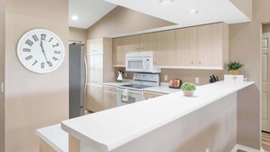 Una cocina moderna con una isla central, un microondas y un reloj en la pared.