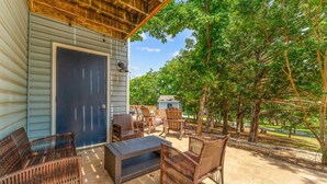 A covered patio with wicker furniture, a small shed, and a view of trees. - Pools/ Hot Tub / Whispering Woods Retreat (Branson)