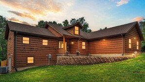 A log cabin with a stone foundation, multiple windows, and a porch. - Teal’s Treasure – Secluded Lakeside Cabin for 8! (Kirbyville)