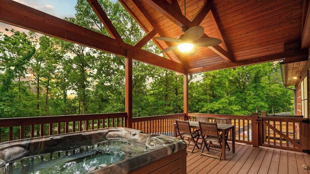 A hot tub on a wooden deck with a ceiling fan, surrounded by trees. - Teal’s Treasure – Secluded Lakeside Cabin for 8! (Kirbyville)