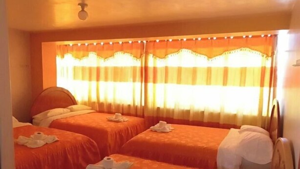 Une chambre d’hôtel avec deux lits, un ventilateur de plafond et une fenêtre avec des rideaux.