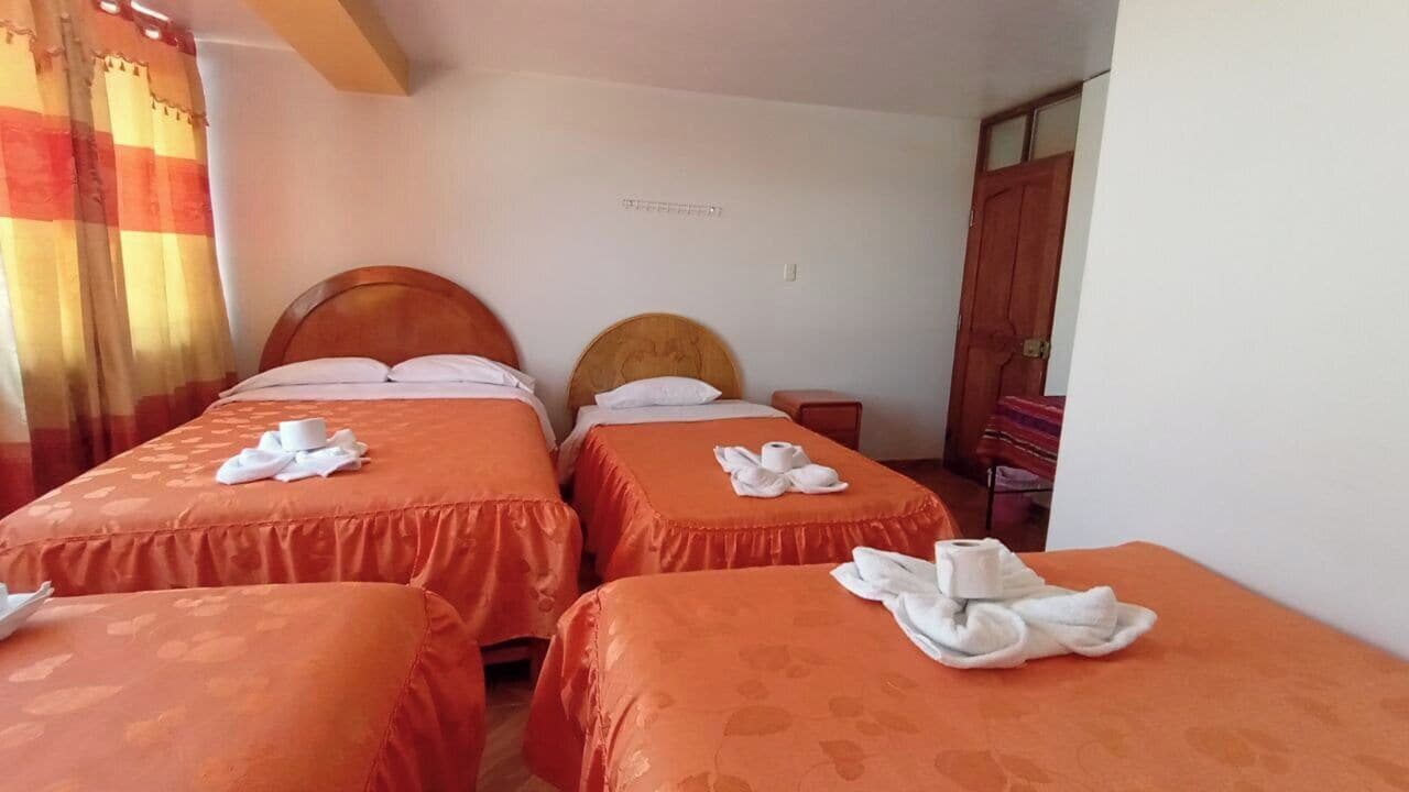 A hotel room with two beds, each with a neatly folded towel and a small table beside them.
