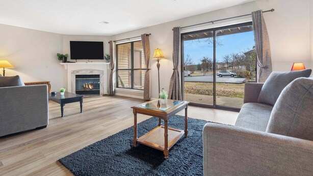 A modern living room with a fireplace, a flat-screen TV, and a large window with curtains. - All Fore the Best | Onsite amenities (Branson)