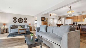 A spacious living room with a grey sofa, a coffee table, and a dining area with wooden chairs and a table. - All Fore the Best | Onsite amenities (Branson)