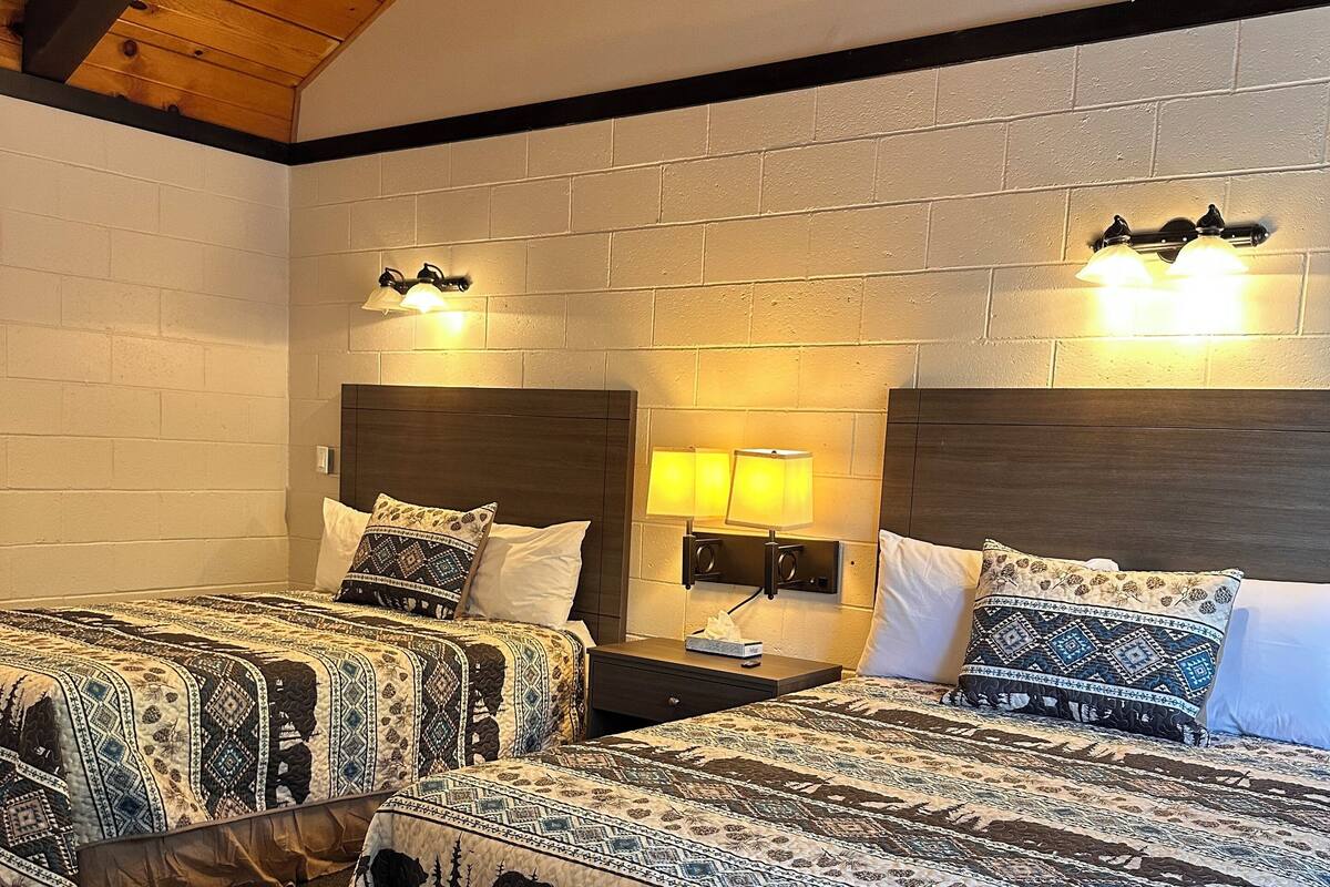 Habitación de hotel con dos camas, techo de madera y paredes de ladrillo.