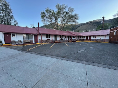A motel with multiple rooms, a parking lot, and a hilly backdrop.. Lee Vining Motel