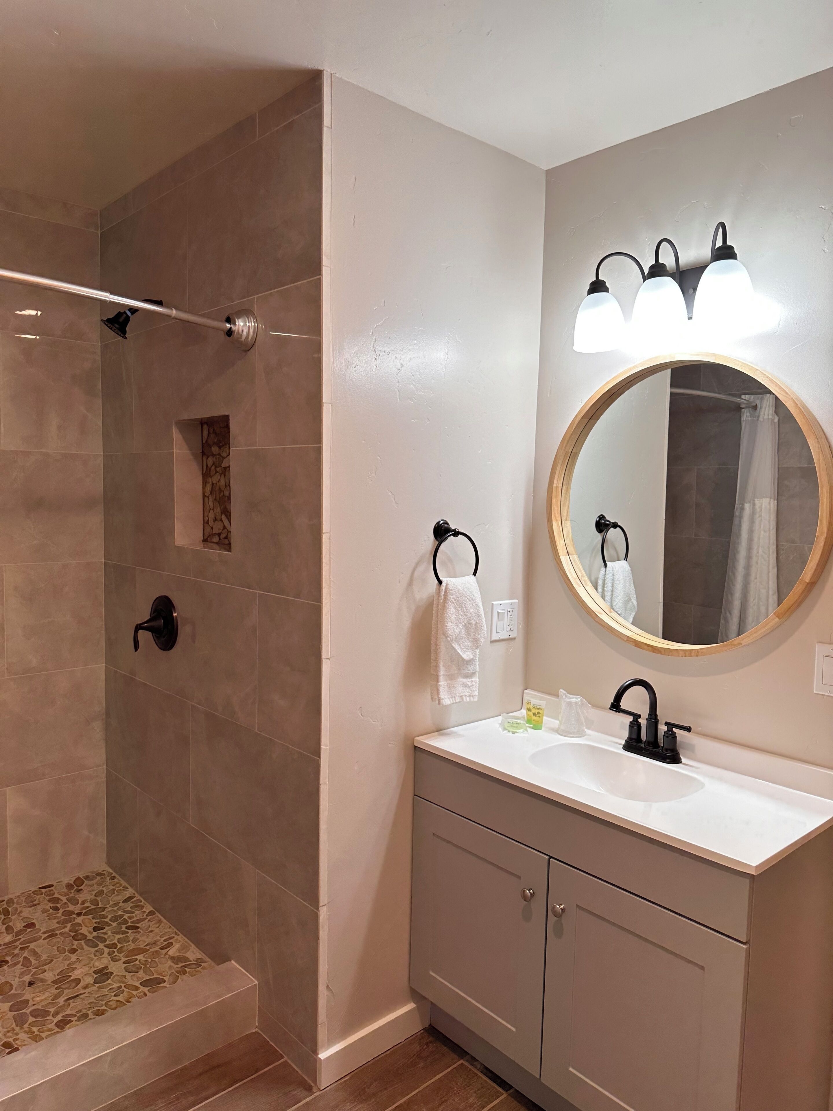 A bathroom with a shower, a sink with a mirror, and a towel rack.