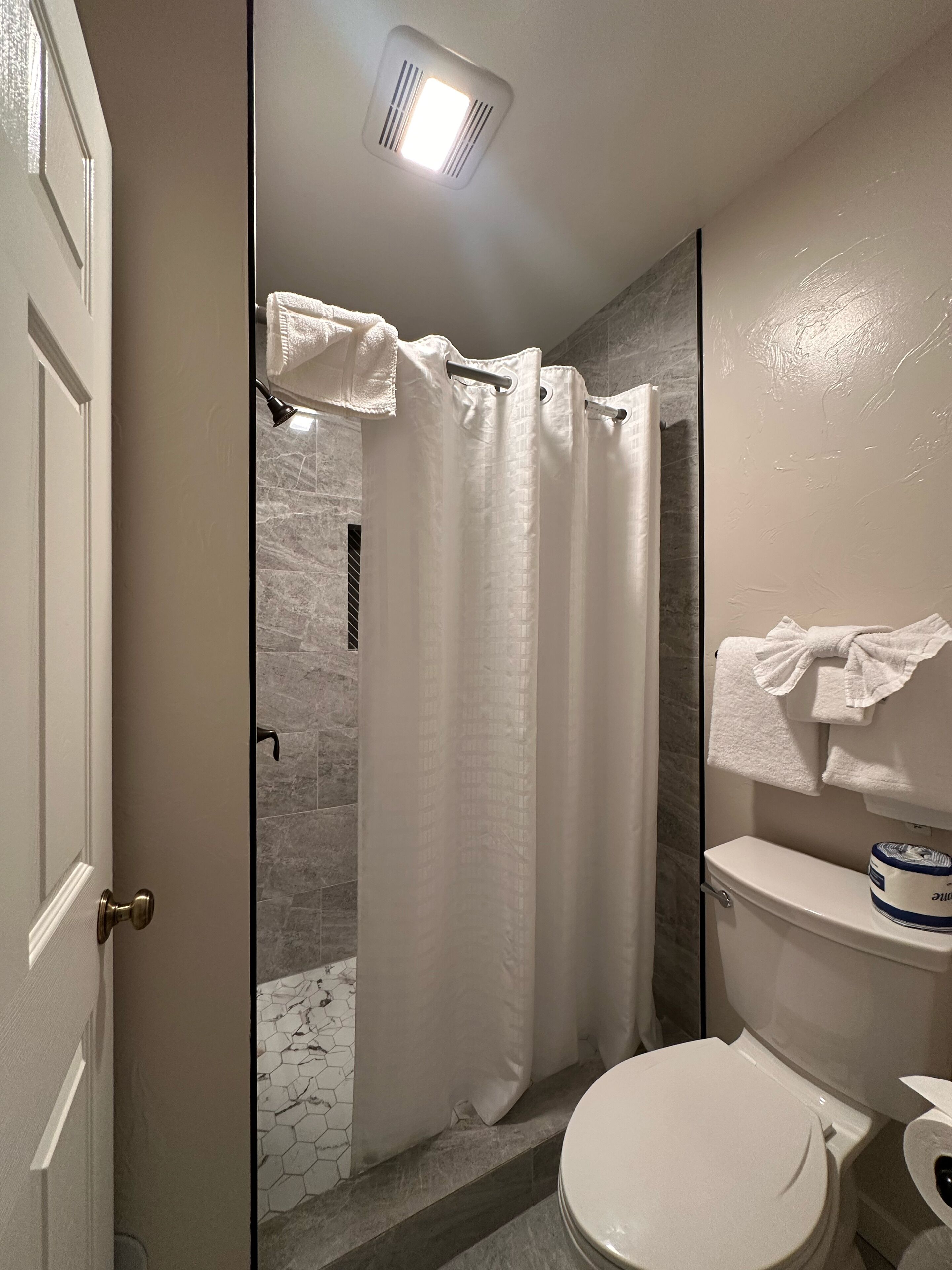A bathroom with a shower, toilet, and towel rack.