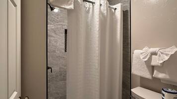 A bathroom with a shower, toilet, and towel rack.