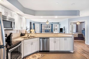 Una cocina moderna con armarios blancos, electrodomésticos de acero inoxidable y una isla central.
