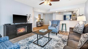 A living room with a fireplace, a ceiling fan, a TV, and a dining area in the background. - Brookside Haven – Gorgeous, Private Community! (Branson)