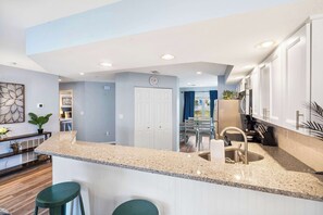 A modern kitchen with granite countertops, white cabinetry, and a central island with bar stools. - Brookside Haven – Gorgeous, Private Community! (Branson)
