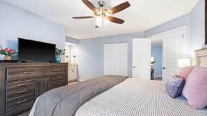 A bedroom with a bed, a dresser, a ceiling fan, and a television. - Brookside Haven – Gorgeous, Private Community! (Branson)