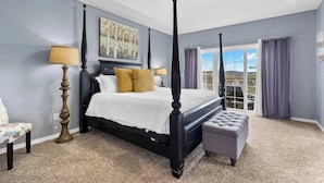 A bedroom with a four-poster bed, a nightstand, a lamp, and a view of the outdoors. - The Greenview Manor - Lake View - 9 Miles from Silver Dollar City (Kimberling City)