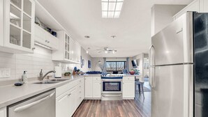 A modern kitchen with white cabinetry, a stainless steel refrigerator, and a wooden floor. - Bright Stylish Condo w/ Balcony (Branson)