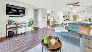 A modern living room with a grey sofa, a coffee table, and a TV mounted on the wall. - Bright Stylish Condo w/ Balcony (Branson)