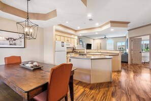 A spacious kitchen with a central island, wooden dining table, and chairs.