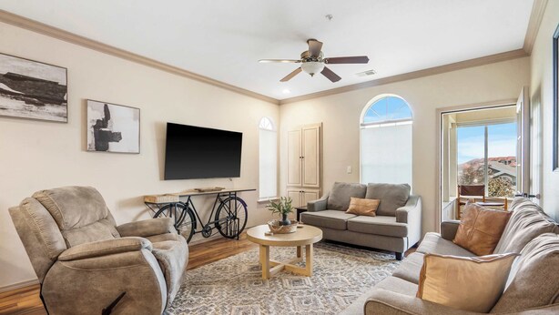 A spacious living room with a ceiling fan, a flat-screen TV, and a large window offering a view of the outdoors. - Glorious Relaxation| Golf Course Views (Branson)