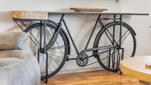 Una bicicleta colgada en un soporte de pared con un estante de madera encima.