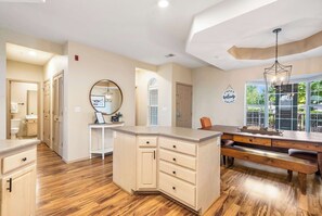 A spacious kitchen with wooden flooring, a central island with drawers, a dining area with benches, and a large window providing natural light. - Glorious Relaxation| Golf Course Views (Branson)