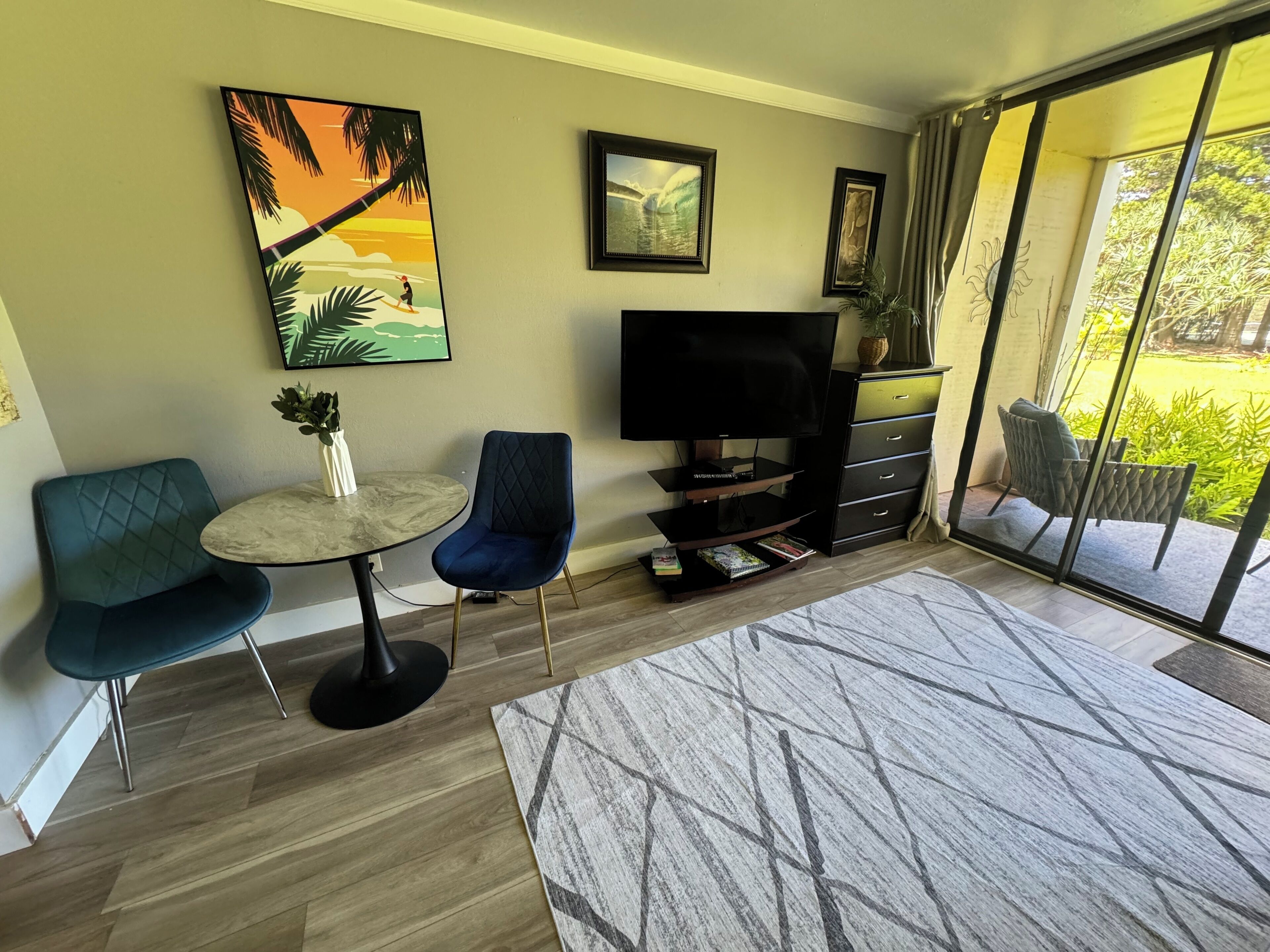 A modern living room with a TV, two chairs, a small table, and a bookshelf.