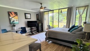Een ruime kamer met een bed, een bureau en een televisie. Een groot raam biedt uitzicht op het omliggende landschap.