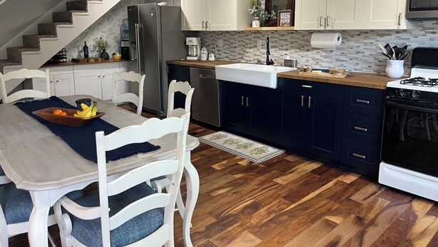 A modern kitchen with a wooden dining table, white chairs, a built-in stove, and a refrigerator. - Charming 3-bedroom house across from Lake Freeman (Monticello)