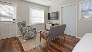 A room with a bed, a chair, a TV, and a cabinet. - Bungalow Near Downtown Orlando, Winter Park, Major Hospitals, and Disney! (Orlando)