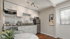 A modern kitchen with white cabinets, stainless steel appliances, and a wooden floor. - Bungalow Near Downtown Orlando, Winter Park, Major Hospitals, and Disney! (Orlando)
