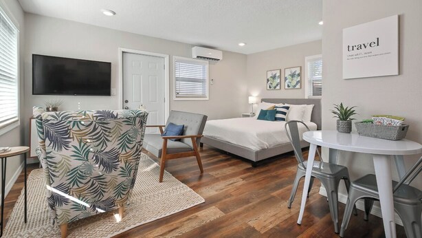 A modern hotel room with a bed, a TV, a desk, and a chair. - Bungalow Near Downtown Orlando, Winter Park, Major Hospitals, and Disney! (Orlando)