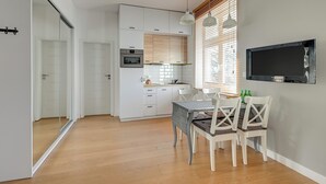 Een moderne keuken met witte kasten, een ingebouwde oven en een eethoek met een tafel en stoelen.