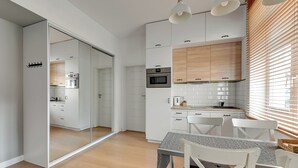 Een moderne keuken met witte kastjes, houten details en een eethoek met een tafel en stoelen.