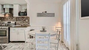 A kitchen with white cabinets, a granite backsplash, a built-in oven, and a microwave. There is a round table with white chairs and a sign above it that reads "HOME SWEET HOME". - Charming 2-bedroom Townhome Near UT Campus/Rosedale (Austin)