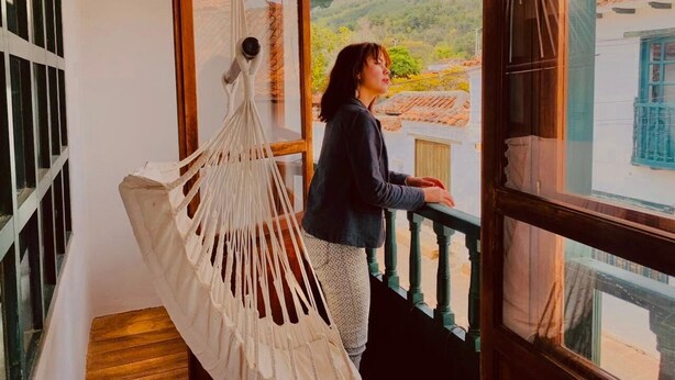 A person standing by a window with a view of a mountainous landscape. - Hotel santone la ville (Villa de Leyva)