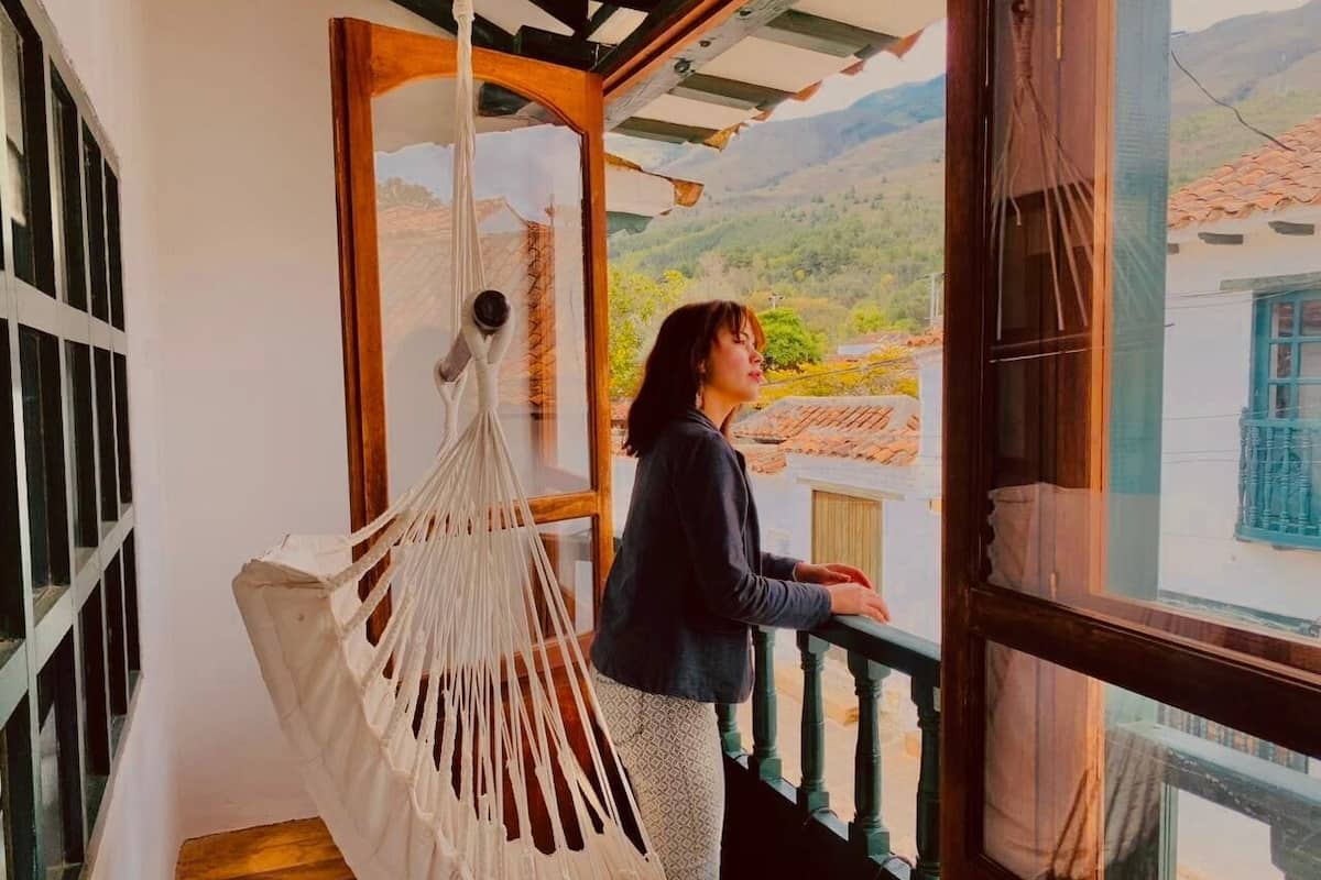 Una persona de pie junto a una ventana con vistas a un paisaje montañoso.