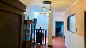 A hallway with a wooden cabinet, a glass display case, and a dining area with a table and chairs. - Hotel santone la ville (Villa de Leyva)