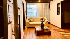 A cozy living room with a sofa, a coffee table, and a window with curtains. - Hotel santone la ville (Villa de Leyva)